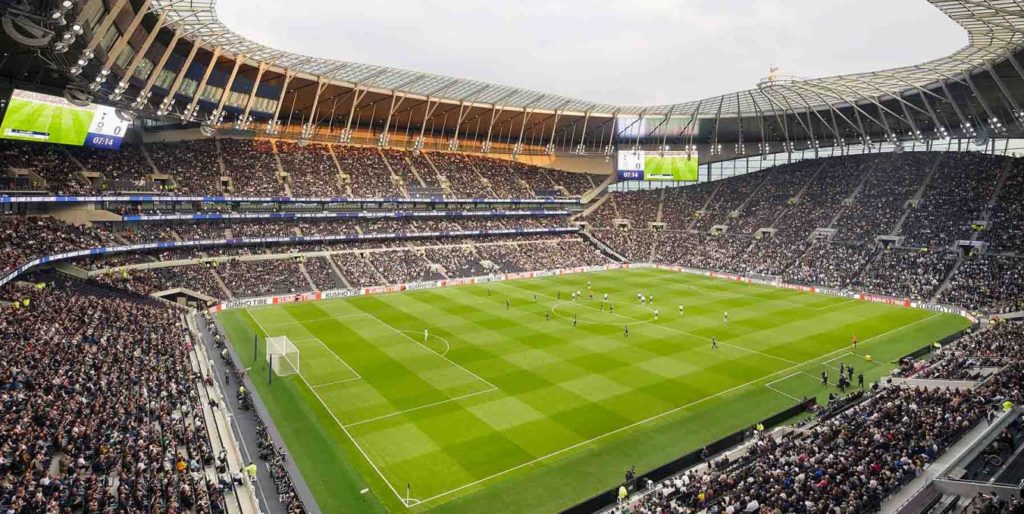 soccer football stadium with players on green pitch with stands full of spectators