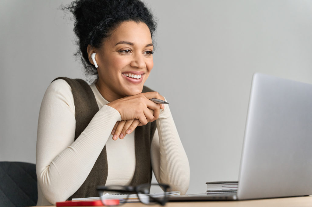 African American mixed race adult female student wearing earphones talking having virtual meeting online call, educational webinar at home office. Video learning conference call on pc.