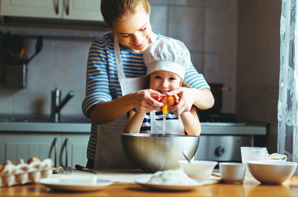 happy family in the kitchen. mother and child daughter preparing the dough, bake cookies