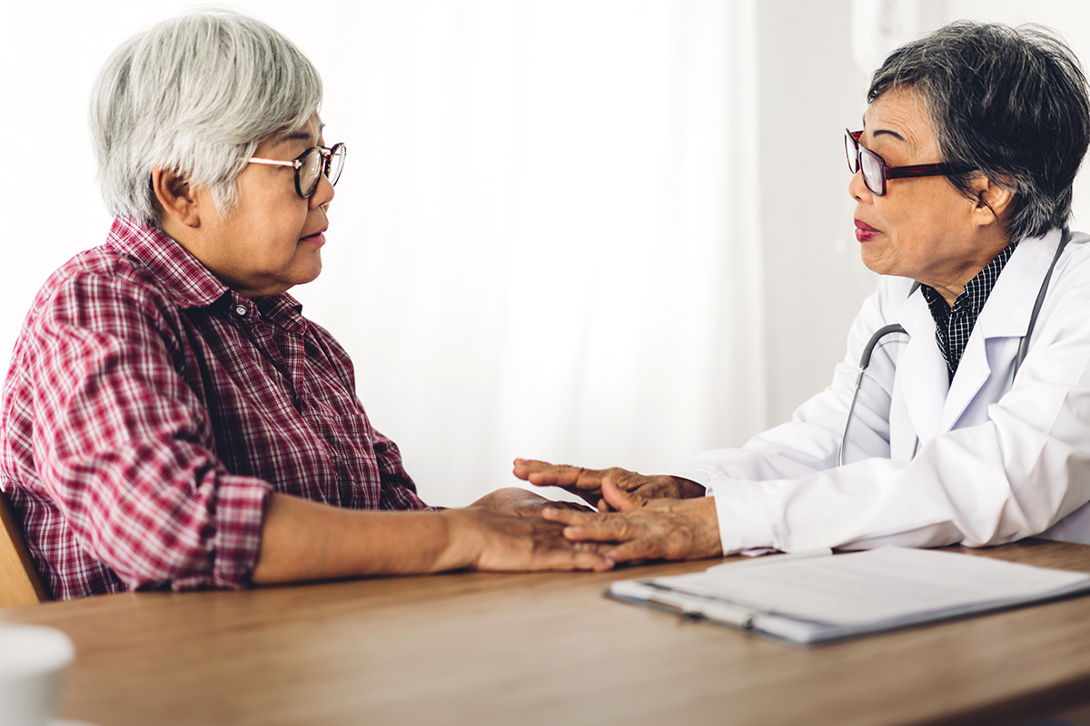 Female senior doctor consulting and holding hand senior woman patient reassuring with care on doctors table in hospital.healthcare and medicine