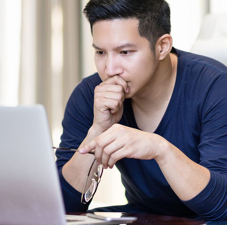 confident asian young freelancer in smart casual working and concentrated on laptop sitting on desk in modern office
