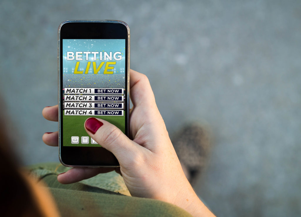 Top view of woman walking in the street using her mobile phone with bet online website. All screen graphics are made up.