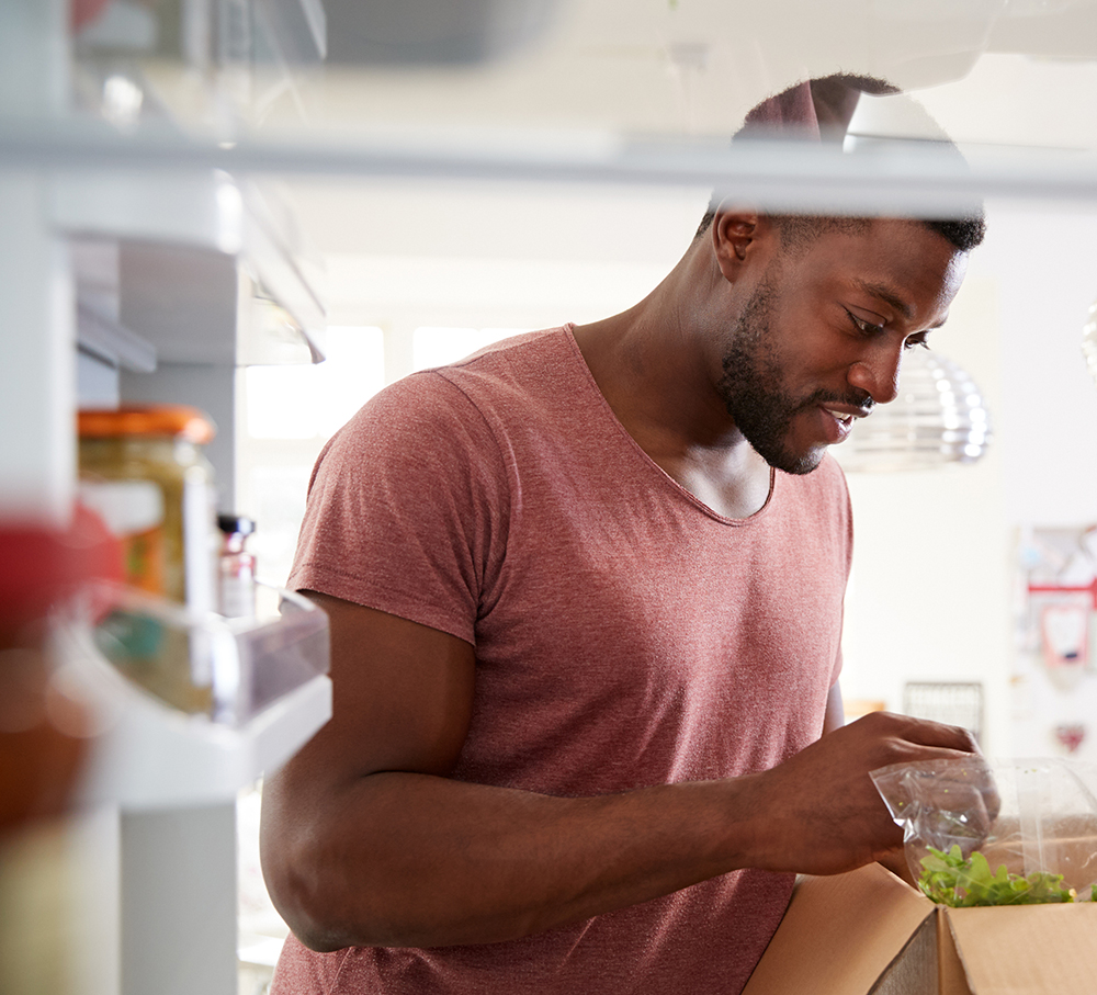 View Looking Out From Inside Of Refrigerator As Man Unpacks Online Home Food Delivery